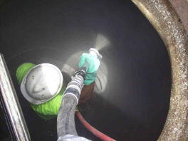 Spraying restoration mortar using shotcrete equipment onto corroded manhole